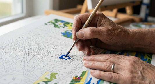 A close up of hands carefully painting a detailed adult paint by numbers canvas, showing the precise grip and focus involved in the hobby
