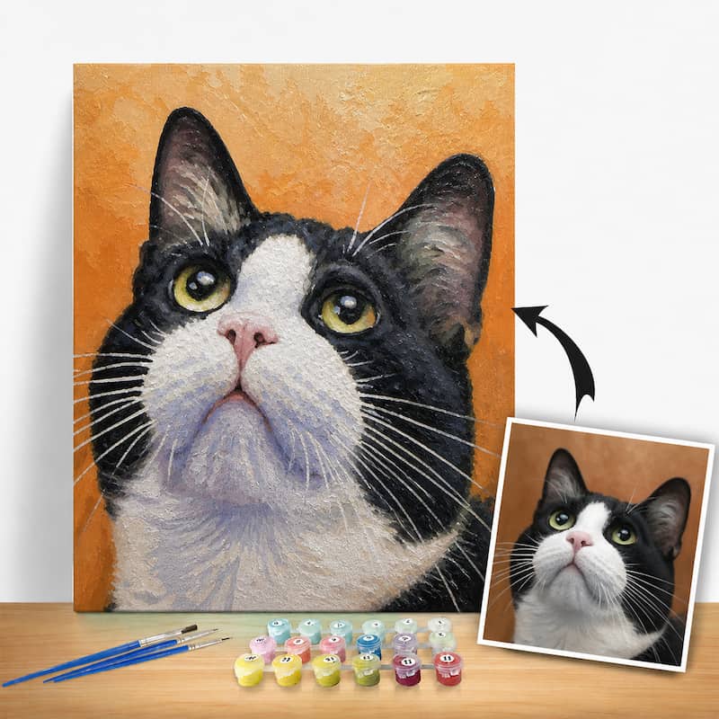Detailed painting of a black and white cat with a smaller inset photo, surrounded by art supplies on a wooden surface.