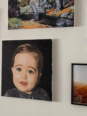 Framed artwork on a wall, including a portrait of a child and landscape paintings.